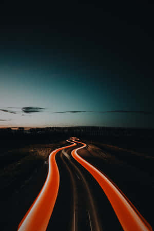 黃昏時分的蜿蜒道路，帶有汽車發出的橙色光軌。