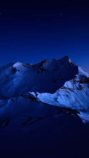 白雪覆蓋的山脈與蜿蜒的道路，在星空下。 — iPhone 7 壁紙