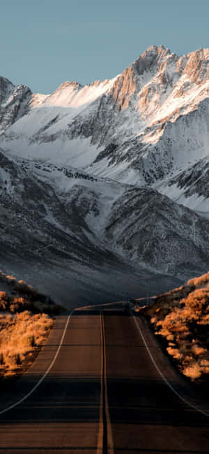 一條通往日落時分雪山的道路。 — Huawei 壁紙