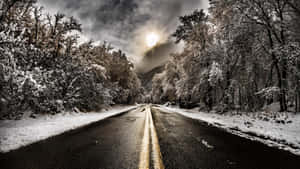 在戲劇性的冬日天空下，兩旁是結霜樹木的雪路。 — 道路 壁紙