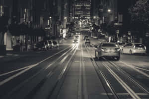 夜景城市街道，街燈下有汽車和電車軌道。 — MacBook Pro 壁紙
