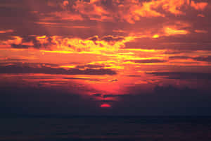 海洋上的夕陽，帶有熾熱的橙色和紅色雲彩