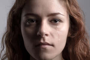 一位紅髮女性流下一滴淚水順著臉頰。