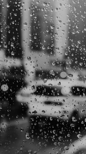 窗戶上的雨滴，背後可見模糊的城市燈光和濕漉漉的人行道。