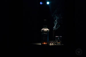 威士忌酒瓶和酒杯，煙霧在黑暗聚光燈環境中升起 — 黑色動態圖 壁紙