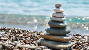 卵石海灘上堆疊的石頭，伴隨著海浪 — 森林景色 壁紙
