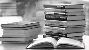 一疊工程和技術教科書，桌上有一本打開的書。 — 書籍 壁紙