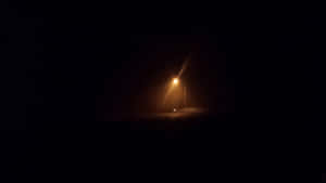 一盞孤獨的街燈照亮了霧夜場景，圍欄和道路處於陰影中。 — 迷幻暗黑風格 壁紙