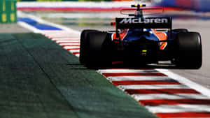麥拿倫F1賽車在設有紅、白、綠色路緣石的賽道上疾馳。