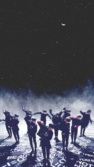 K-pop 團體在星空下以新月為背景表演。