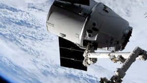 SpaceX龍飛船在地球上空的軌道上，機械臂伸展。 — 外太空 壁紙