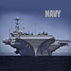 一艘大型灰色海軍航空母艦在海洋上航行，上方有NAVY文字。 — iPad (A16) 壁紙
