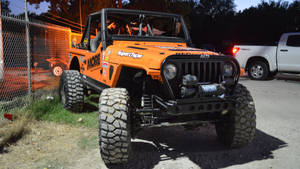 橙色越野Jeep在黃昏時停泊在圍欄附近 — 汽車 壁紙