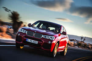 日落時分在沙漠公路上疾馳的紅色BMW X4，背景模糊。 — 平治 C300 壁紙