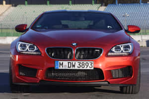 紅色BMW M6跑車在賽道上，後面是空曠的體育場座位。 — Surface Laptop 壁紙