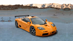 橙色McLaren F1超級跑車在沙漠景觀中，背景有山脈和日落。 — 4K 法拉利 壁紙