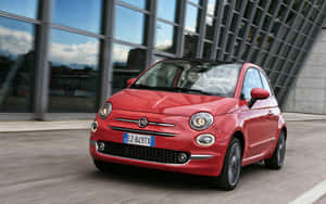 紅色Fiat 500汽車在陽光明媚的日子駛過玻璃建築。 — MacBook Air M1 壁紙