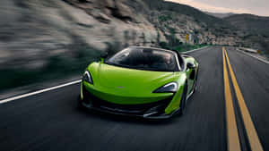 一輛綠色McLaren跑車在日落時分的山路上奔馳。 — 日落 壁紙