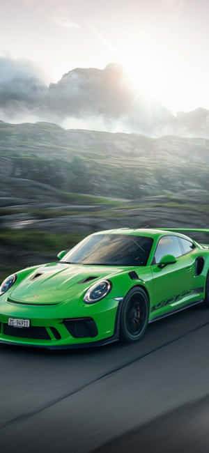 綠色保時捷 GT2 RS 在日落時分的山路上疾馳。 — Redmi Note 14 Pro 壁紙