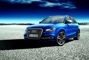 藍色 Audi SQ5 SUV 停放在礫石上，背景是暮色天空。 — 奧迪 GIF 壁紙