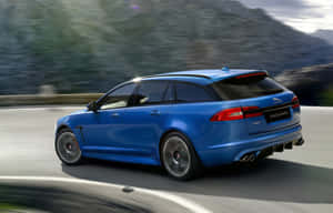 藍色Jaguar XF Sportbrake在日落時分的山路上疾馳 — Steam Deck OLED 壁紙