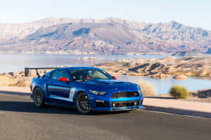 藍色福特Mustang GT350R停泊在沙漠湖邊，背後有山脈。 — Surface Laptop 壁紙