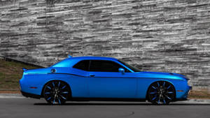 一輛閃亮的藍色肌肉車停在石牆旁邊。 — Dodge challenger GIF 壁紙