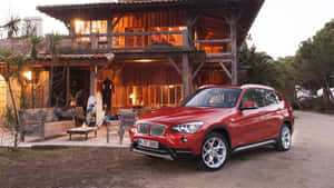 黃昏時分停在質樸木屋前的紅色BMW X1 SUV。 — 奧迪 GIF 壁紙