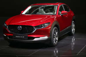 在攝影棚環境中，紅色Mazda CX-30 SUV停在反光的黑色地板上。 — MacBook Air 15 壁紙
