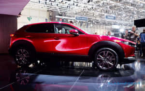 紅色萬事得CX-30 SUV在車展上展示，拋光地板上有倒影。 — 1280x800 壁紙
