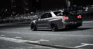 啞光灰色日產Skyline R34跑車，紅色尾燈，夜晚停在城市街道上。 — Jdm 美學 壁紙