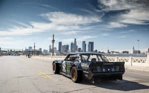 黑色漂移車帶有Monster Energy品牌標誌，位於橋上，背景為城市天際線。 — Steam Deck OLED 壁紙