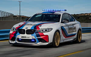 白色BMW M2 Coupe安全車帶藍紅條紋在賽道上奔馳 — MacBook Pro M1 壁紙