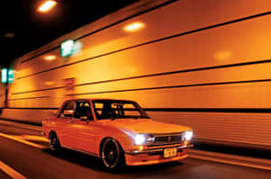 橙色復古車在夜間高速穿過明亮的隧道。 — 紅色美學 壁紙