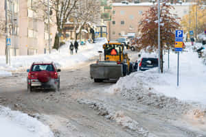 掃雪車清理城市街道上的積雪，附近有汽車和行人。 — MacBook Air 15 壁紙