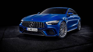 在攝影棚燈光下，黑色瓷磚地板上的藍色 Mercedes-AMG GT 跑車。 — 藍色 壁紙