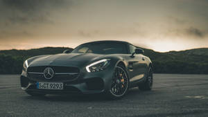啞光黑色梅賽德斯-AMG GT跑車停在日落時的瀝青路上。 — 汽車 壁紙