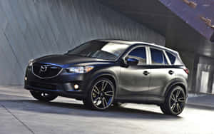 啞光黑色萬事得 CX-5 SUV 停放在現代混凝土結構下。 — Steam Deck OLED 壁紙