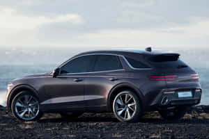 深灰色 Genesis GV70 SUV 在日落時停泊在黑色沙灘上，靠近海洋。 — 新世紀福音戰士 壁紙