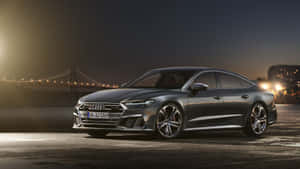 一輛深灰色奧迪轎車在夜間停泊，背後有一座亮燈的橋樑。 — Audi R8 GIF 壁紙