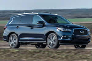 深藍色 Infiniti SUV 在鄉間小路上行駛，背景有綠色田野和山丘。 — 3:2 壁紙