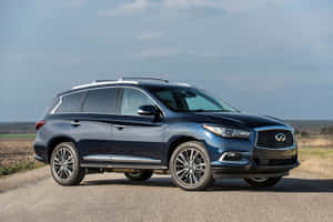 深藍色 Infiniti QX60 SUV 停泊在碎石路上，背景有開闊的田野和多雲的天空。 — Surface Pro 壁紙