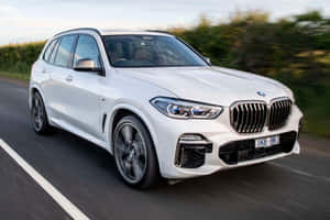 白色BMW X5 SUV在鄉村道路上行駛，帶有動態模糊效果。 — Surface Laptop 壁紙