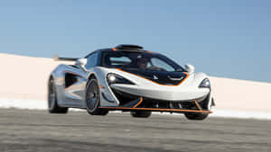 白色McLaren超級跑車帶有橙色點綴在賽道上比賽。 — 4K 法拉利 壁紙