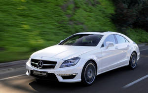 白色Mercedes-AMG CLS Coupe在綠樹成蔭的道路上疾馳。 — 汽車 壁紙