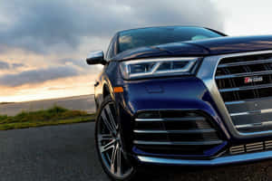 藍色 Audi SQ5 SUV 在日落時分停在路上，伴隨著戲劇性的雲彩。 — 奧迪 GIF 壁紙