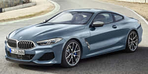 時尚的藍色BMW 8系轎跑車行駛在蜿蜒的道路上，兩旁有礫石和綠樹。 — Audi R8 GIF 壁紙