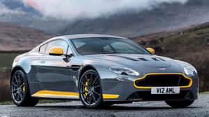 銀色 Aston Martin V12 AMR 帶黃色飾條，停泊在靠近山區的碎石路上。