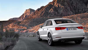 銀色 Audi 房車在沙漠道路上，背景是日落時分的山脈。 — 奧迪 GIF 壁紙