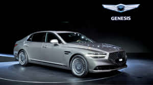 銀色 Genesis 豪華轎車在黑暗舞台上，聚光燈下，帶有品牌標誌。 — Pro Display XDR 壁紙